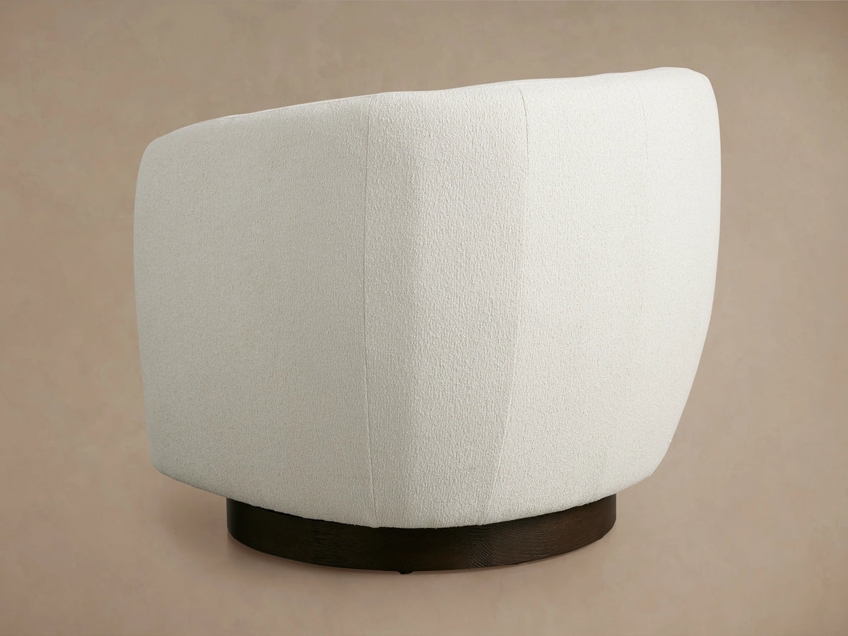 Curved armrest and cushioned seat of the Cerrito Swivel Chair, upholstered in soft cream fabric, showing texture and stitching.
