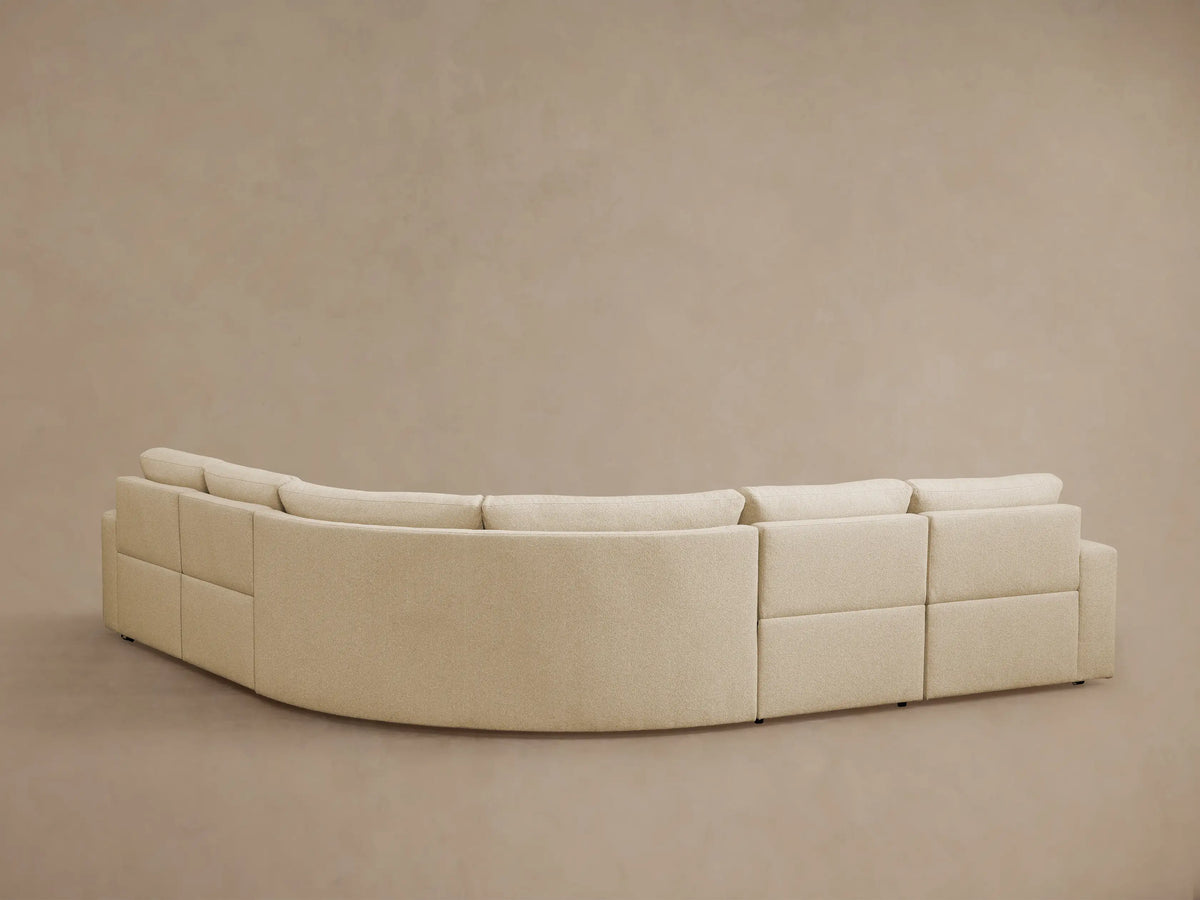 Light beige Brennan 5-piece motion corner sectional, one right-side seat reclined with footrest extended, against a plain wall.
