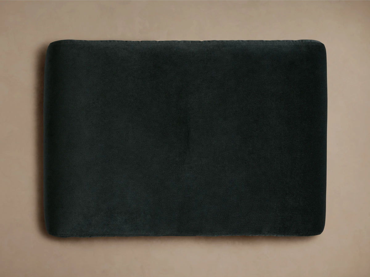 Ryan Ottoman in Banks Midnight, dark upholstered fabric, rectangular shape with a single button tuft on top, positioned on a neutral background.