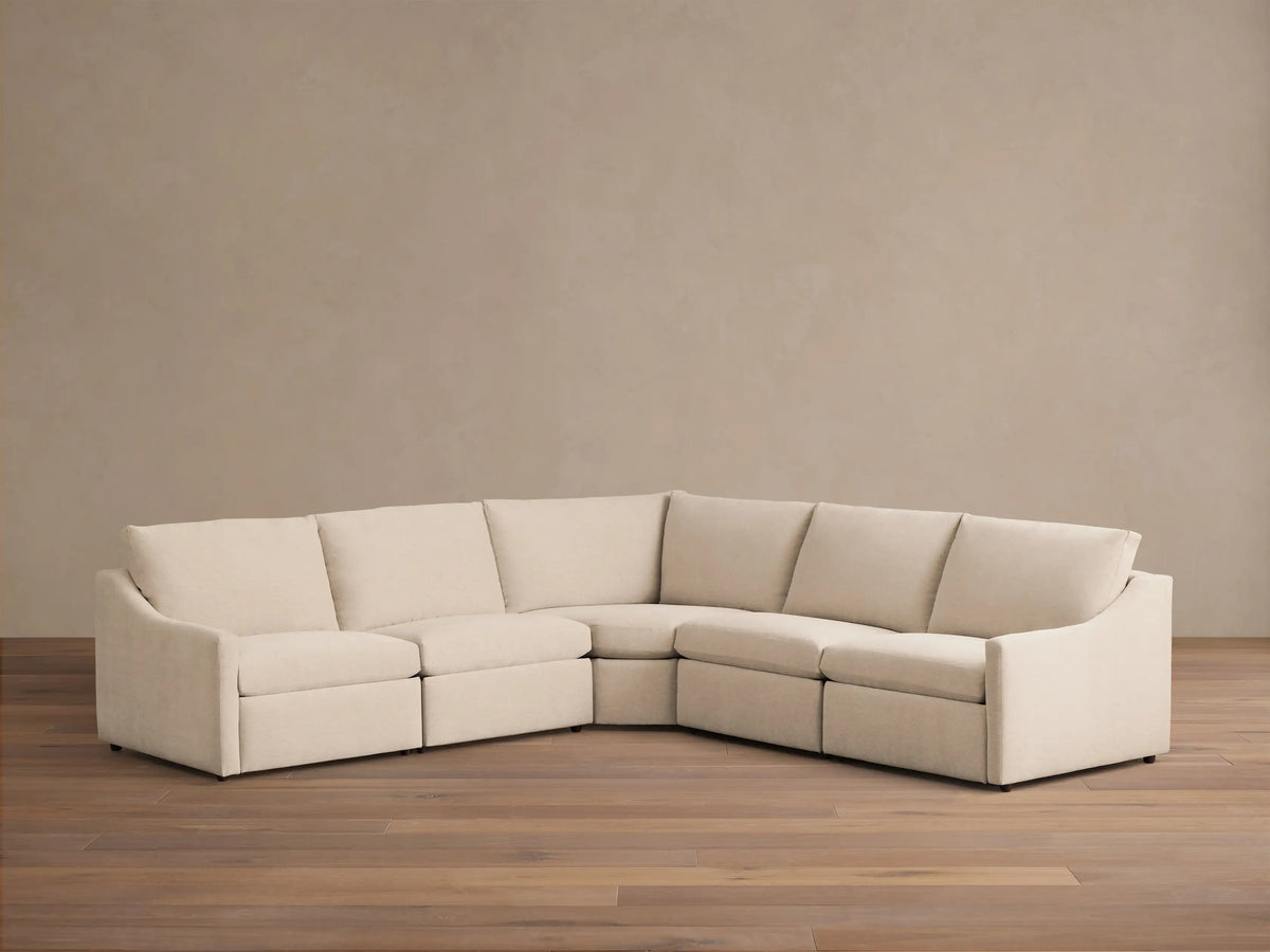 Close-up of a brushed silver two-button motion control on the textured light beige Kipton Slope Arm Five-Piece Motion Corner Sectional.