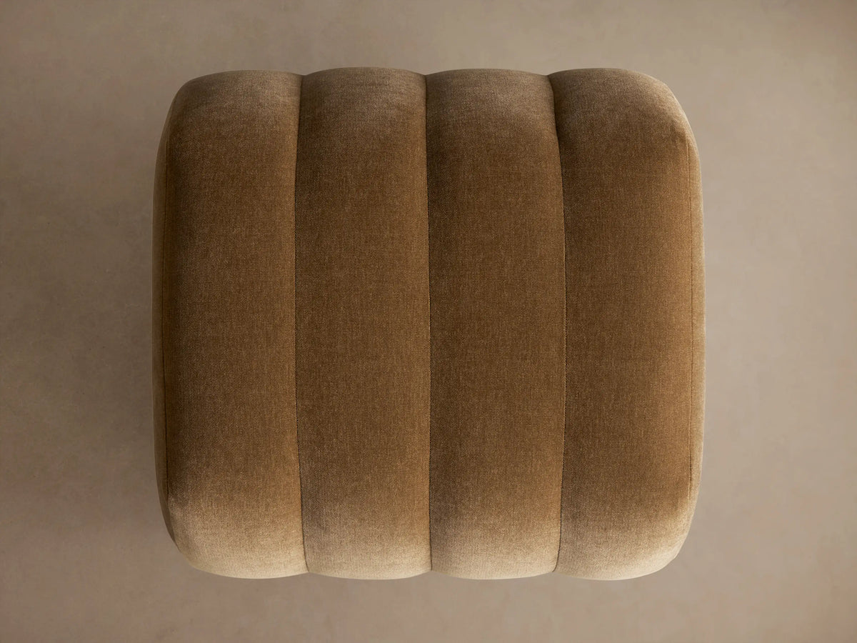 Fresno Channel-Stitched Ottoman, a plush warm brown velvet ottoman with distinct vertical channels and rounded ends.