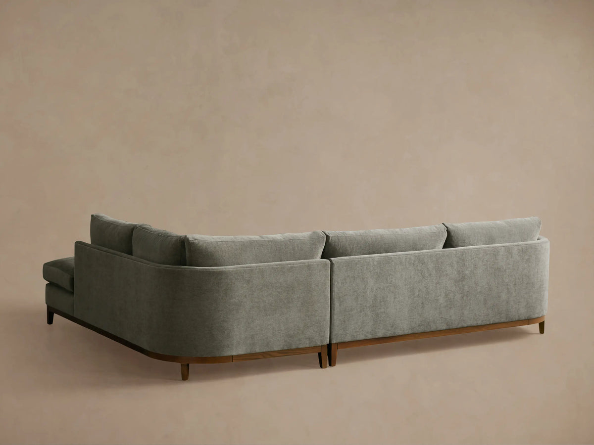 Bainbridge Two-Piece Bumper Sectional, close-up of rounded armrest with textured gray fabric, plush cushions, wooden base.