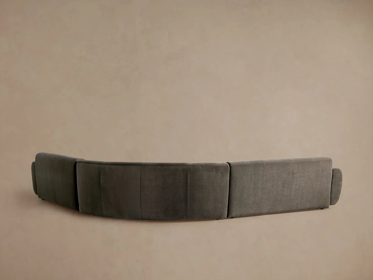 Angled view of a dark charcoal velvet Gianni Three-Piece Corner Sectional, showing soft curves and plush texture.