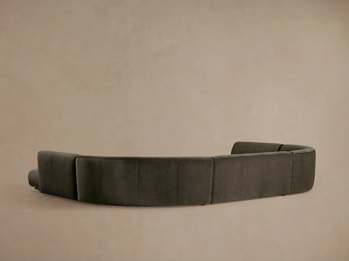 Close-up of Gianni Five-Piece Curved Bumper Sectional, dark grey with a soft texture, flowing curve against a warm neutral background.