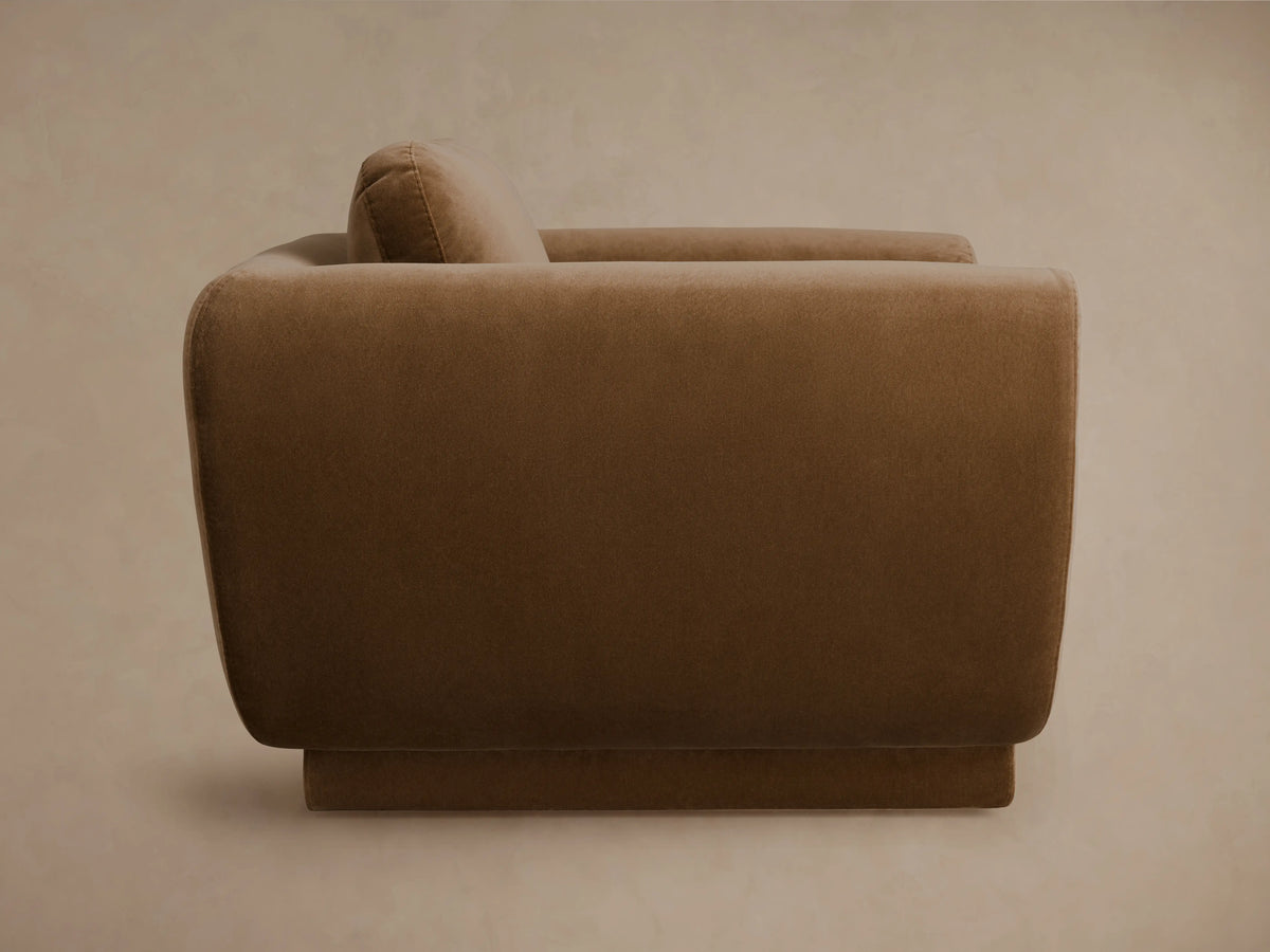 Fontana Swivel Chair, curvy brown fabric armchair with rounded arms, deep seat, and back cushion, on a wooden floor.