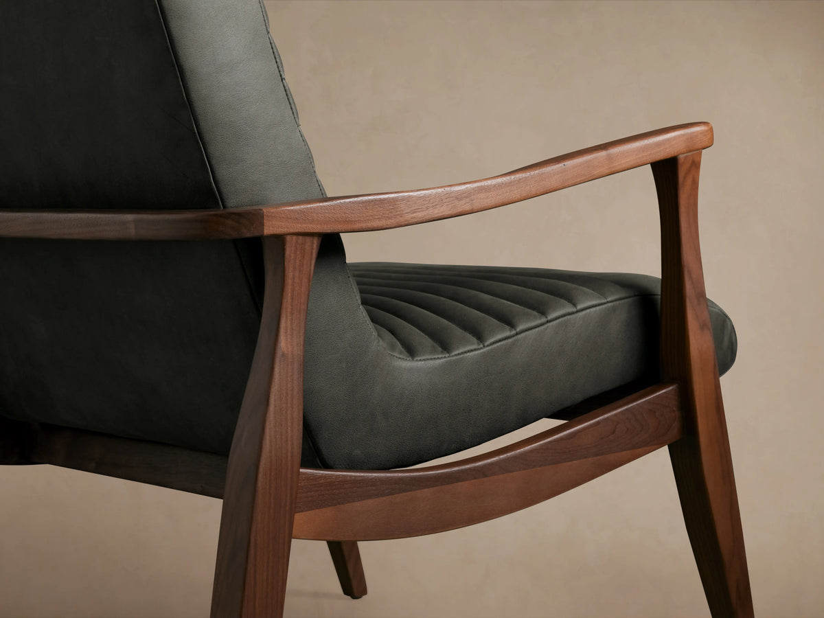 Nathaniel Leather Chair in dark gray leather, viewed from the back. Features wooden arms and legs, with a high backrest on a beige background.