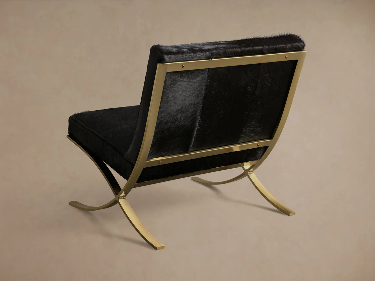 Close-up of the black hair on hide upholstery and curved brass finished stainless steel legs of the Moxie Hair on Hide Chair.