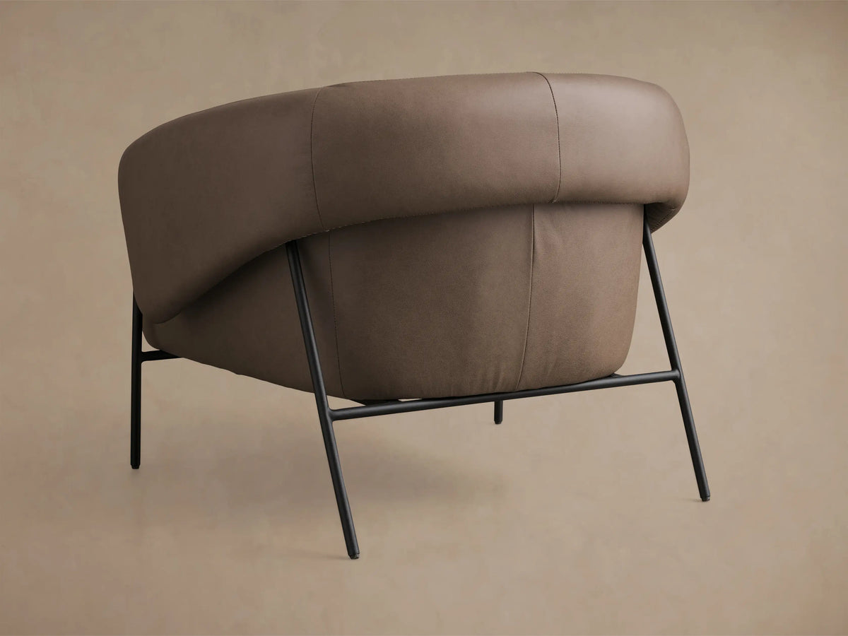 Close-up of the brown leather armrest and seat of the Linus Leather Chair, highlighting detail stitching.