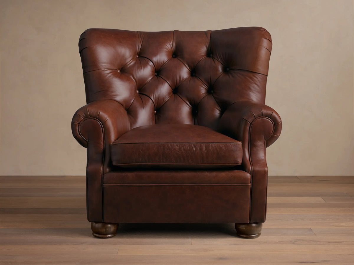 Rear view of a brown leather armchair, showing its curved back, rolled armrests, and small round wooden feet.