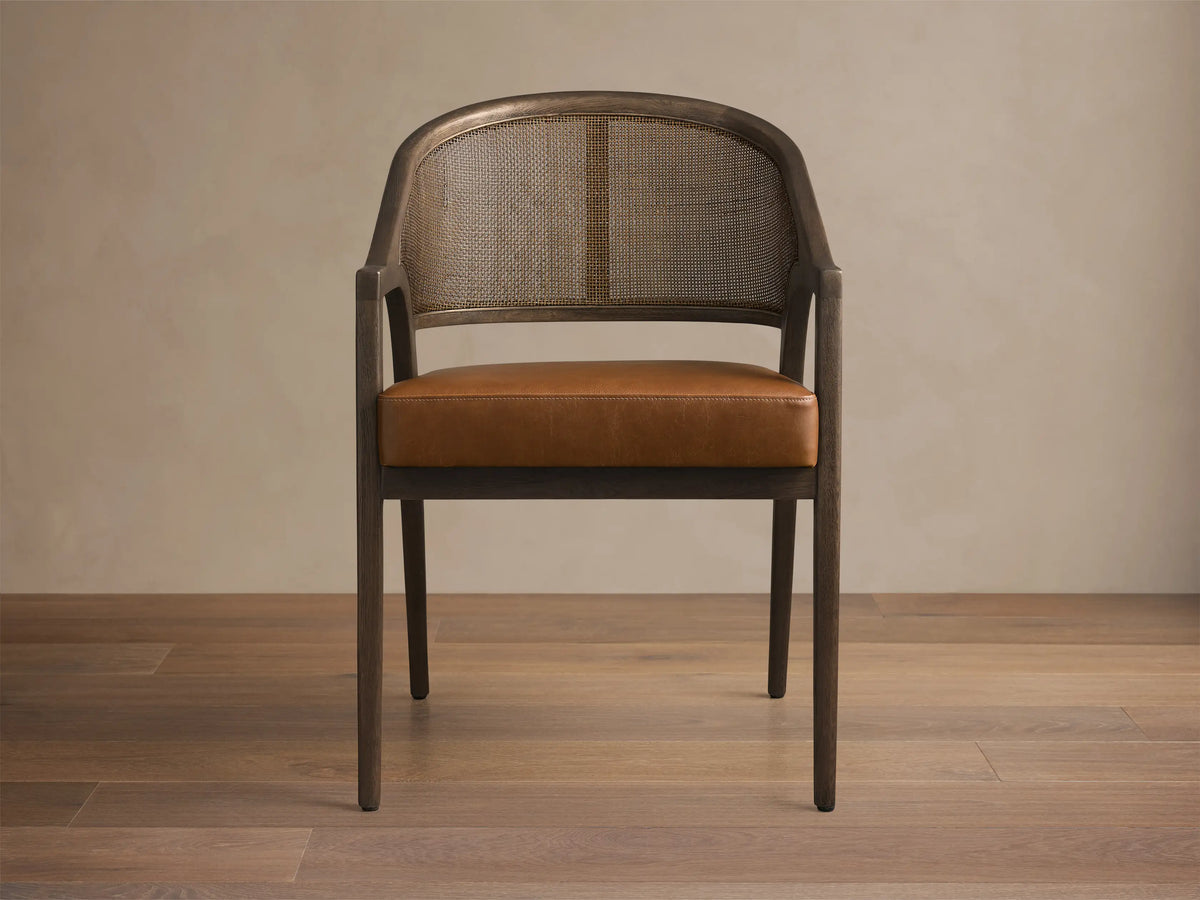 Close-up of the Black Drifted Aimee Faux Leather Dining Arm Chair with dark wood frame, brown rattan cane back, and brown faux leather seat.