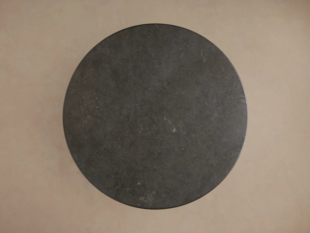 Angled close-up of Amelia Dining Table with a round, dark gray bluestone top and a black oak-grained pedestal base.