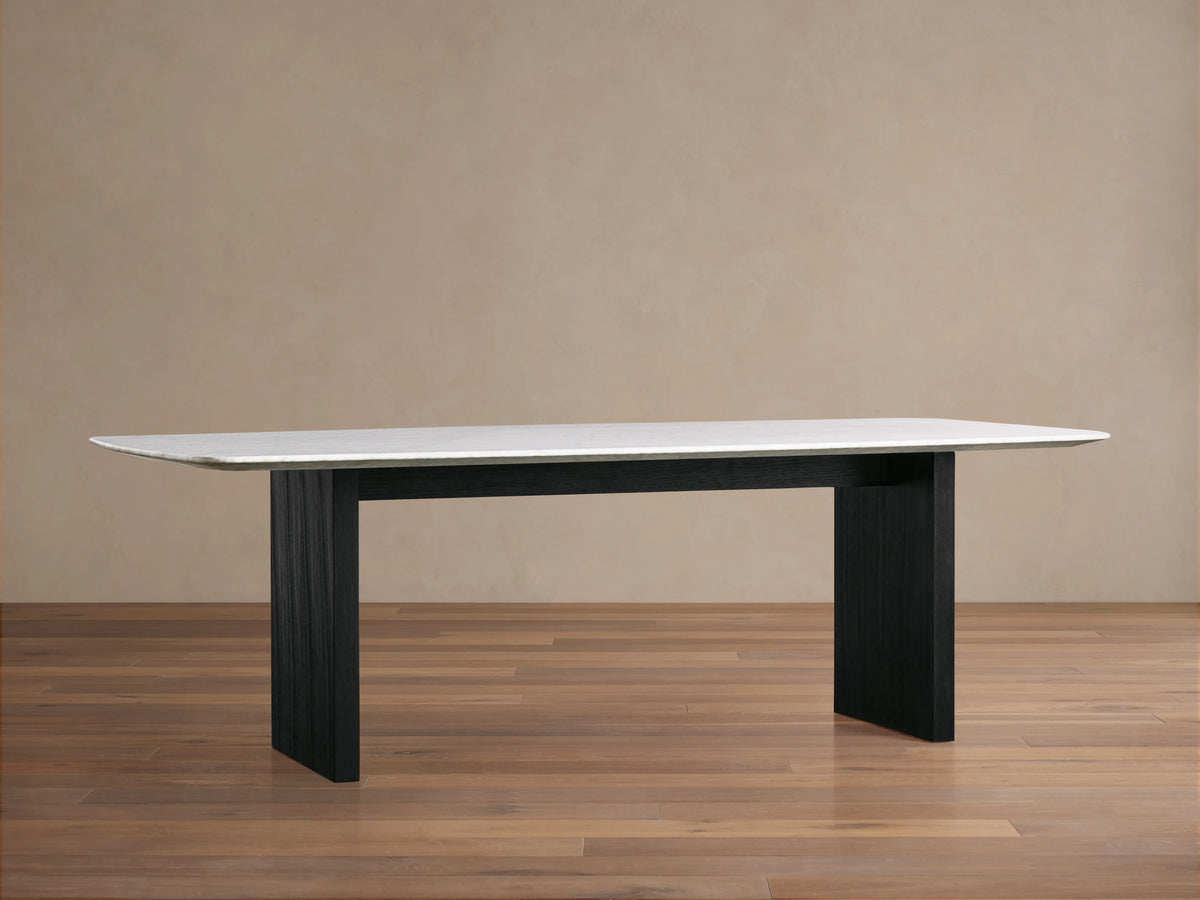Corner of a Saint Germain Dining Table with Carrara marble top showing smooth surface and light gray veining patterns.