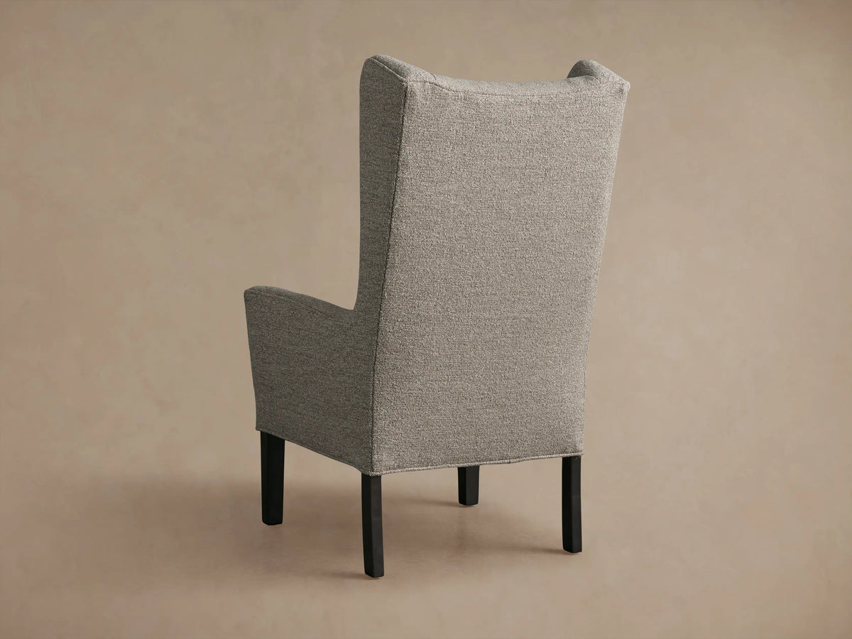 Gray Halstead Dining Chair close-up, showing textured fabric upholstery on seat and backrest, with curved armrests, under soft light.