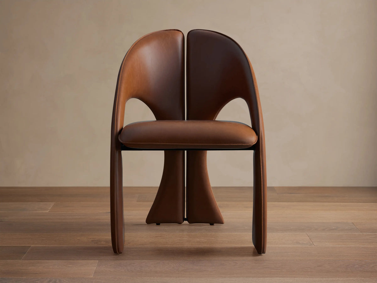 Front view of the brown upholstered Hearst Dining Side Chair with a split, curved back and side cutouts.