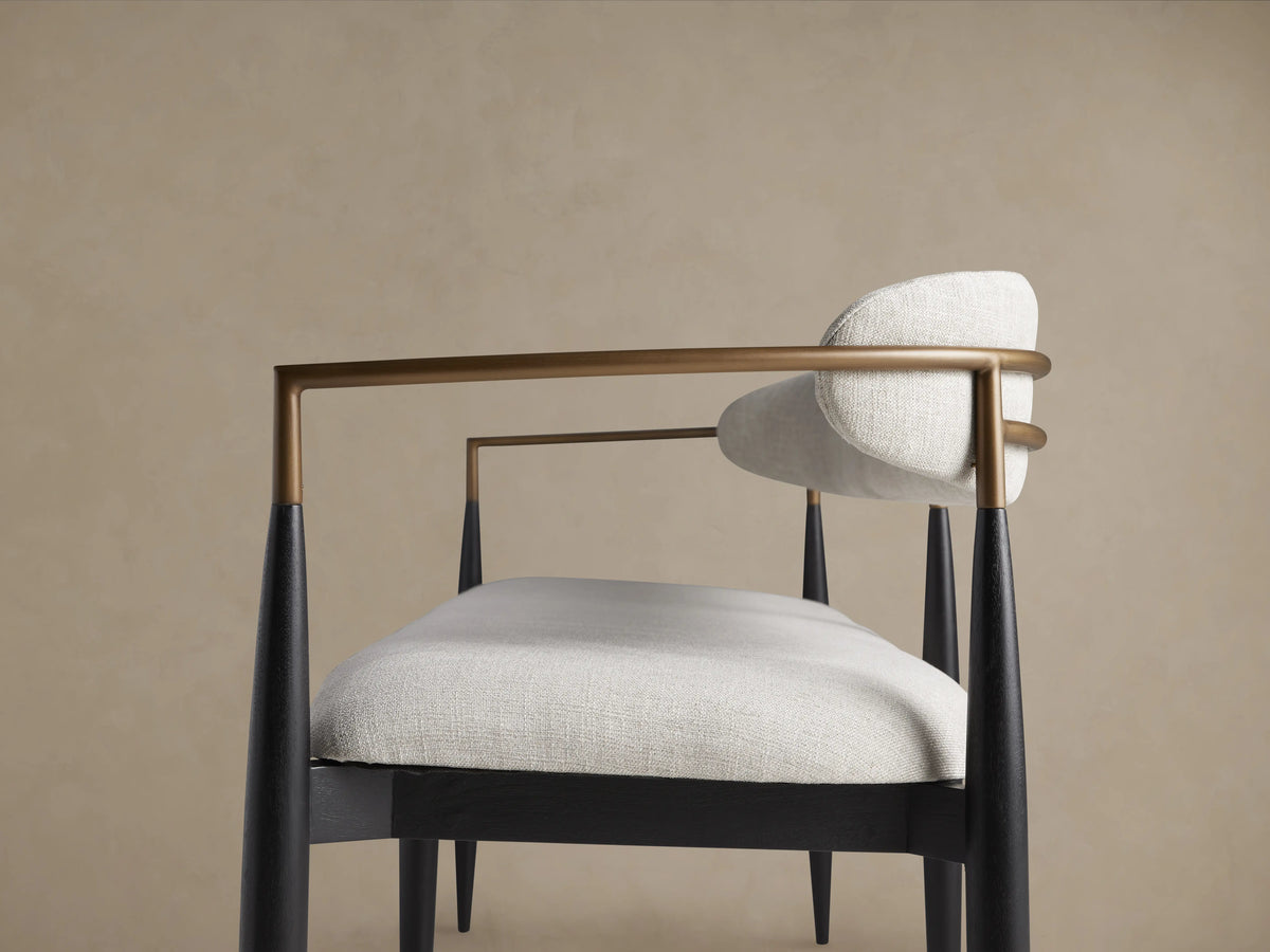 Jagger Dining Bench with light gray cushioned seat and backrest, black slender legs, and wooden floor background.
