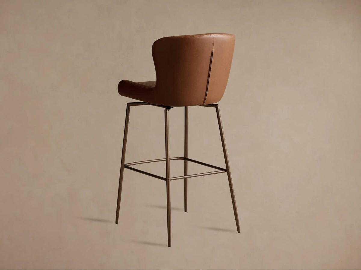 Kirsten Faux Leather Swivel Stool in brown shown in profile. Features a cushioned seat, high backrest, and powder-coated iron legs.