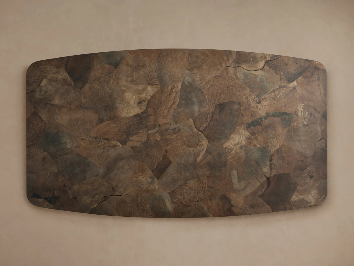 Angled close-up of Polanco Dining Table. Intricate oyster-cut wood tabletop mosaic with varied brown tones & natural graining. Rounded edge, dark base.