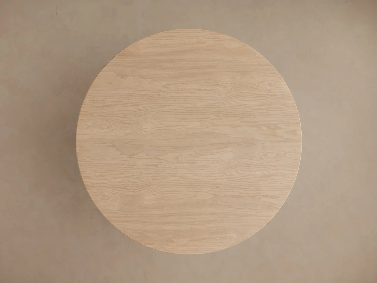 Perth Round Dining Table: close-up of light solid wood with a round top and unique sculpted, bulbous pedestal base, showing wood grain.