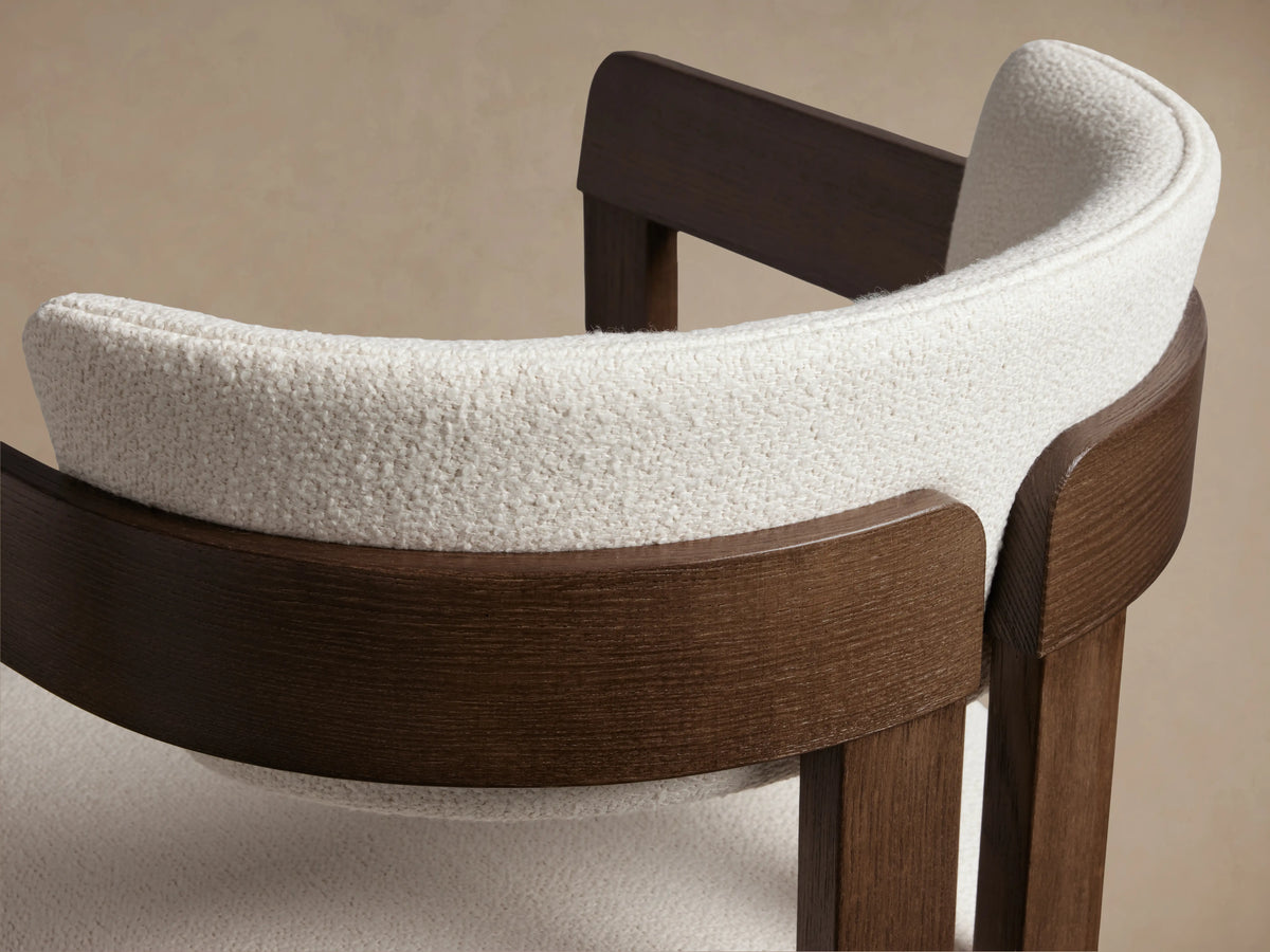 Rodin Stool in side view, featuring dark ash wood frame with curved backrest and white cushioned seat on beige background.