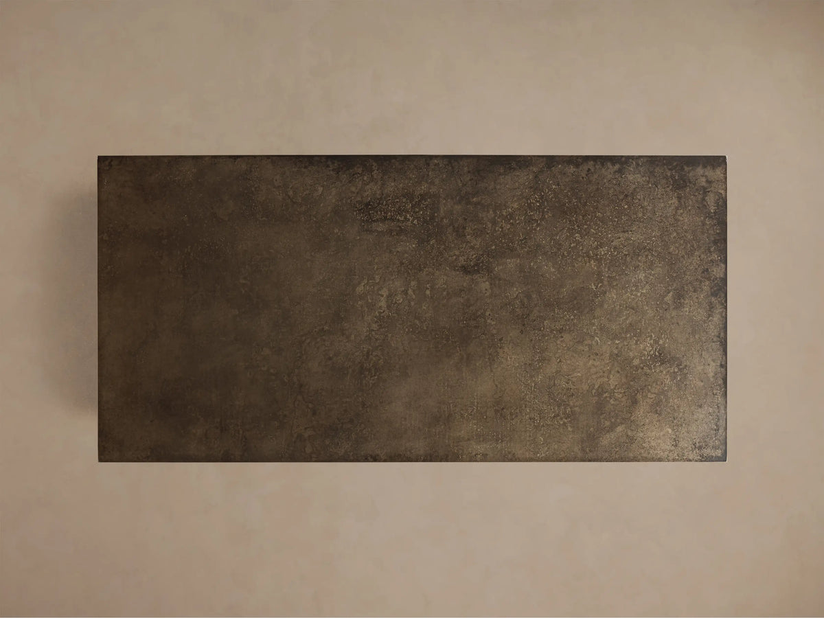 Close-up of a dark bronze, distressed metallic-looking surface with a mottled texture and sharp corner.