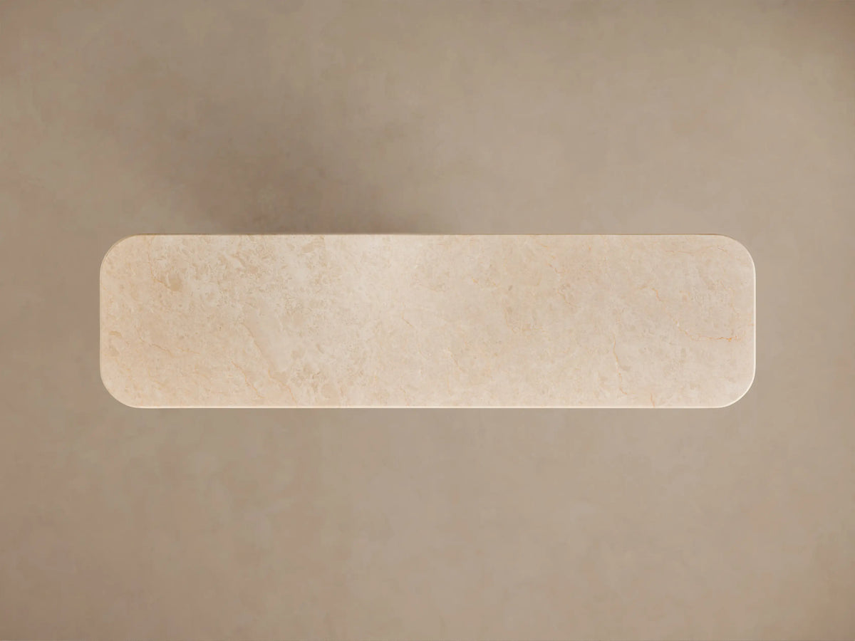 Angled close-up of Caden Console Table. Cream stone top with subtle veining, double rounded edge, light sand oak veneer base.