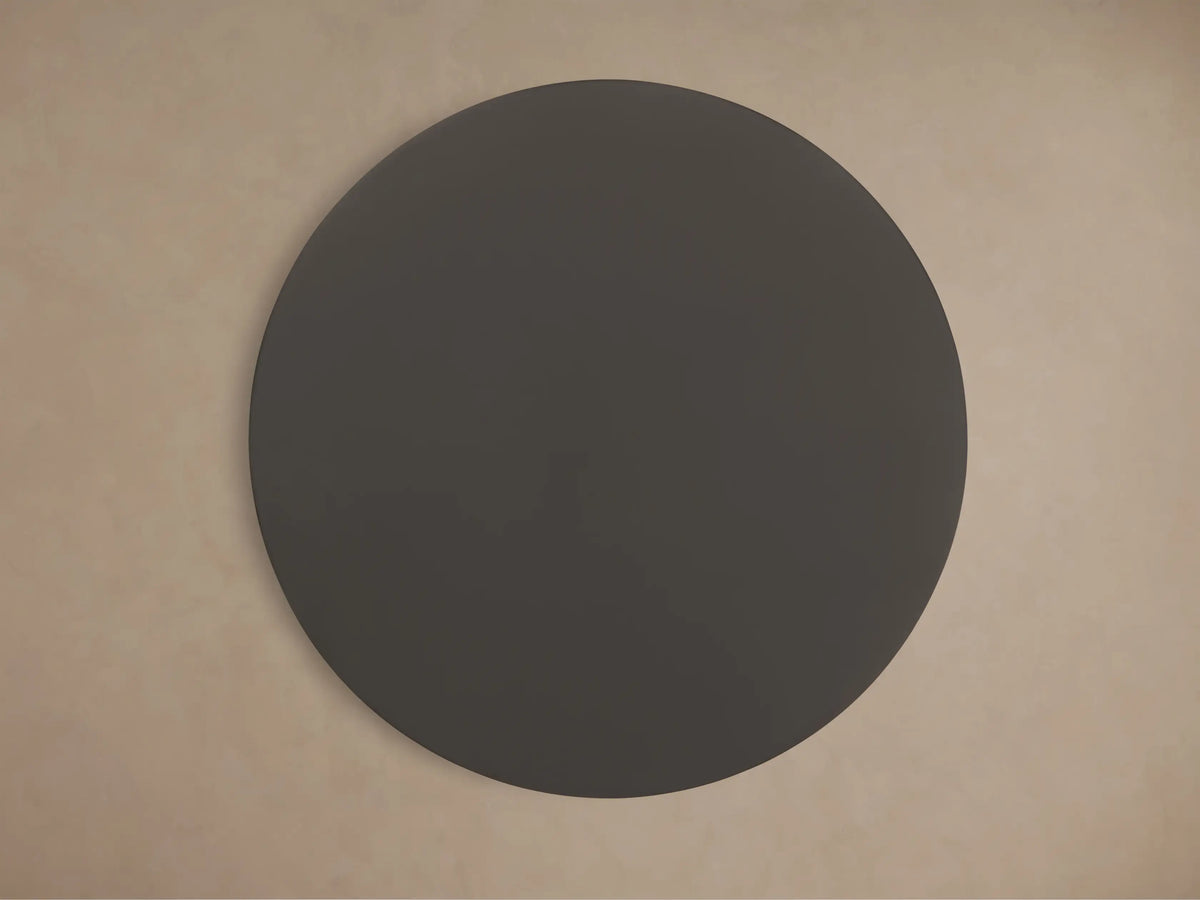 Ferdinand Martini Table with a sleek round black top and metal pedestal base against a beige background.