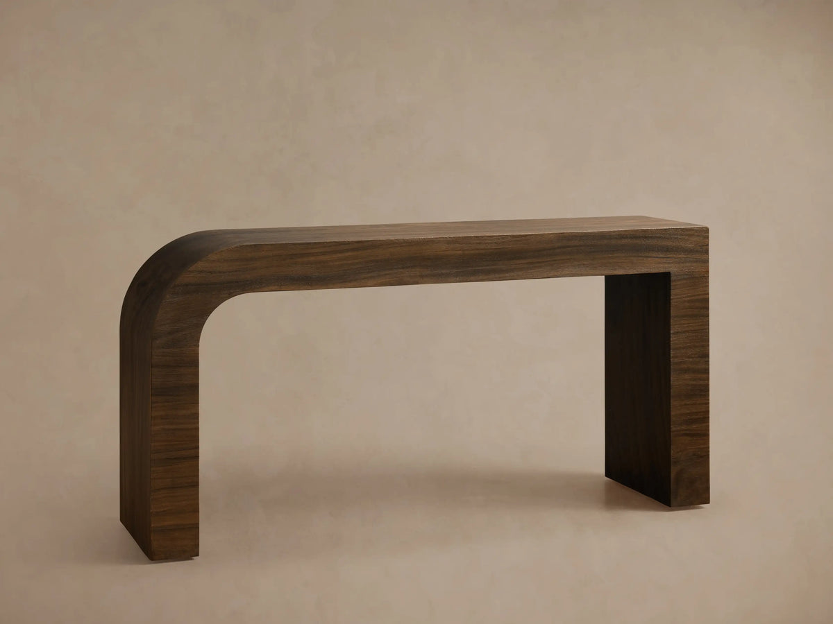 Close-up of Pliego Console Table in dark brown wood, featuring a smooth, continuous curve from top to leg with visible grain.