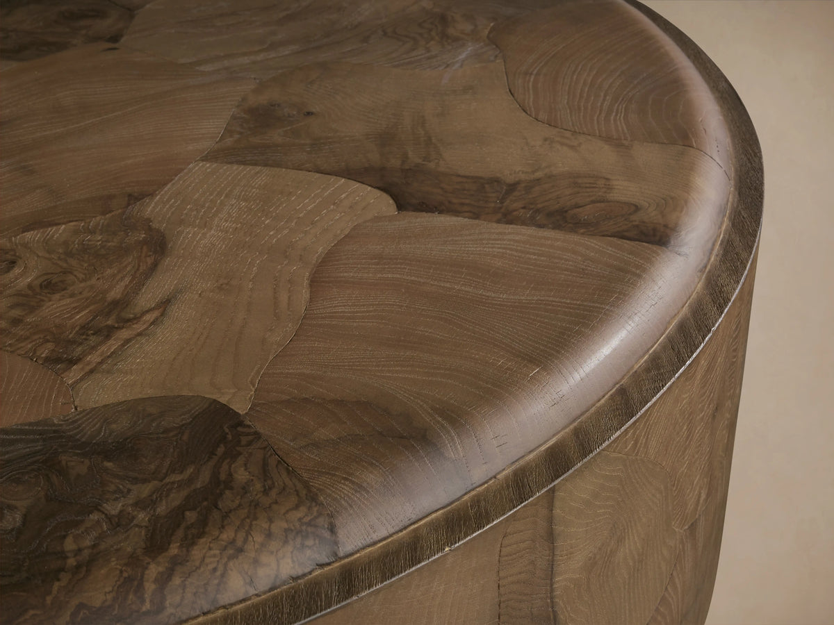 Round coffee table with a smooth, oyster-cut ash wood top and side, featuring natural wood variations and a steel plinth base.