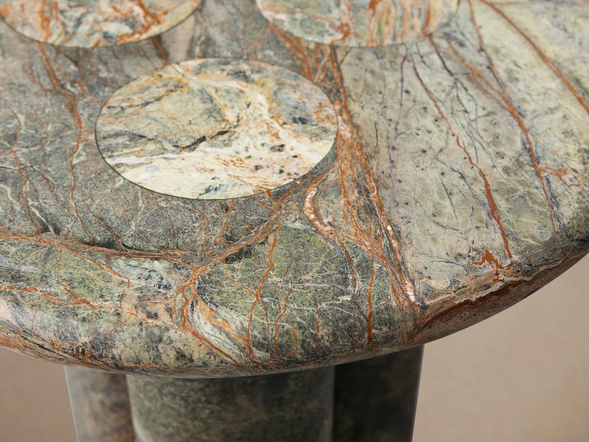 Serafin End Table made of natural stone with round top and three column legs. Features organic veining and color variation.