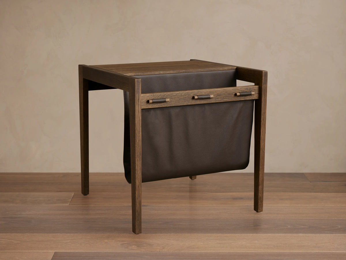 Thorin Magazine Table with solid oak wood frame and brown leather sling, held by wood dowels, for holding magazines.
