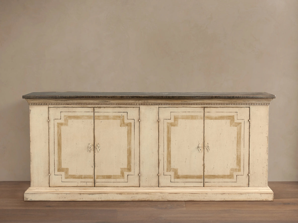 Hand-carved Oriana Buffet with distressed cream finish, showing four lockable doors with one open, revealing shelves inside.