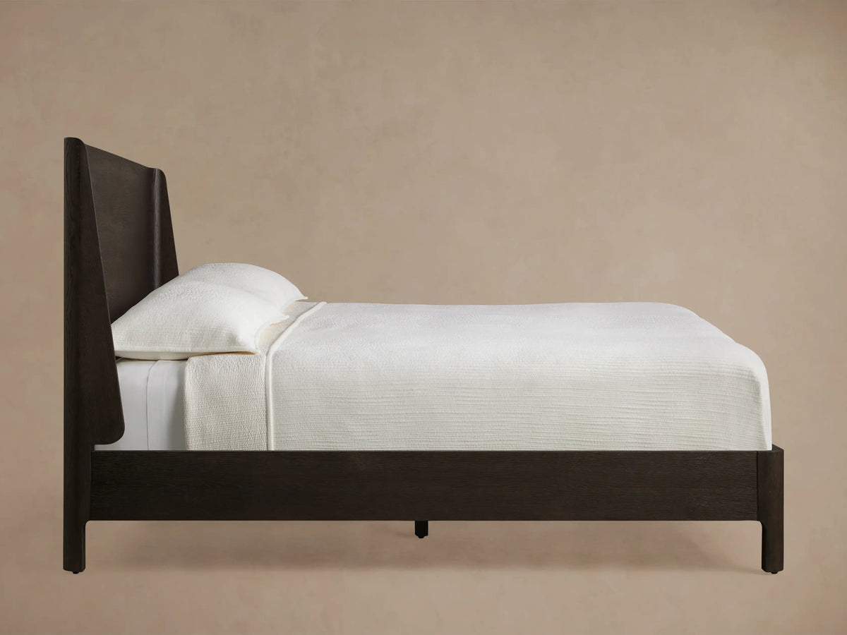 Close-up of Calista Wood Bed headboard in dark espresso veneered oak, showing a curved top edge and corner joinery.