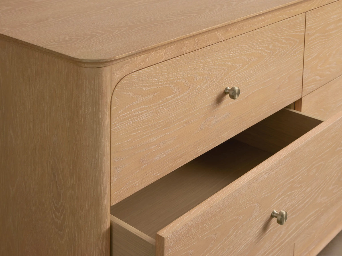 Light oak Conley Nine-Drawer Dresser, 3x3 grid, with champagne brass pulls. Features rounded corners & base curvature.
