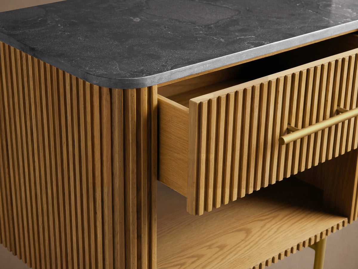 Finnley Open Nightstand in honey oak with reeding, dark stone top, partially open drawer with brass pull, open shelf, brass legs.