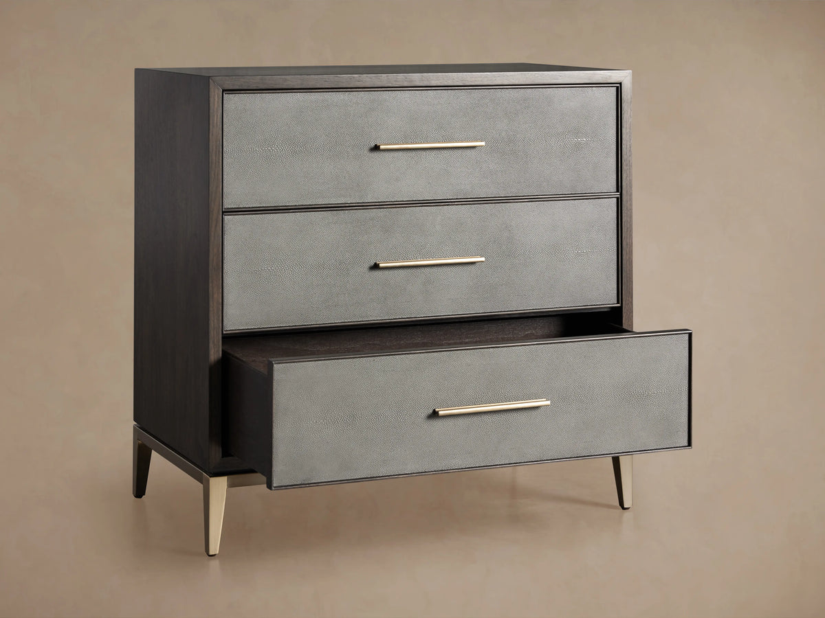 Malone Three-Drawer Chest detail showing a dark wood top and a textured reconstituted leather front with a sleek metallic handle.