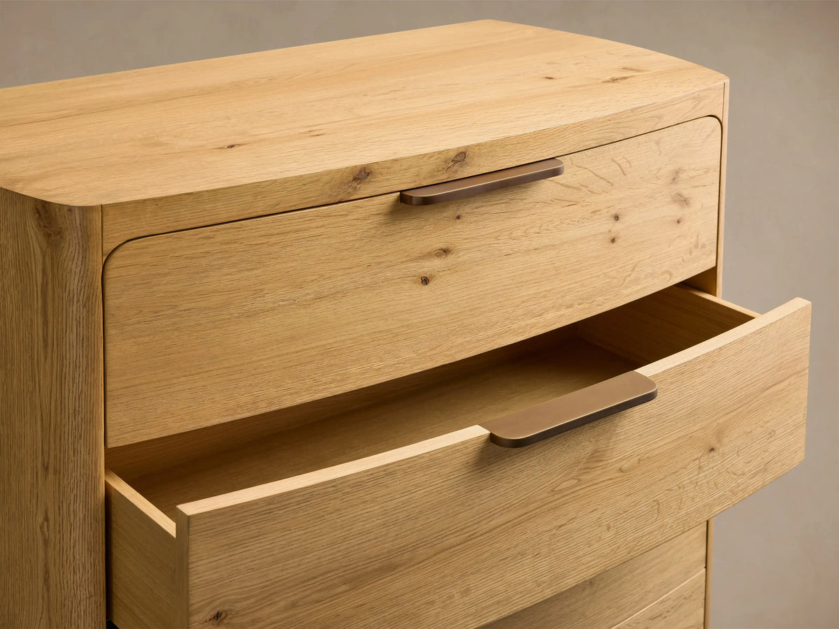 Front view of a natural oak Redding Five-Drawer Dresser with five curved-front drawers and antique brass bar pull hardware.