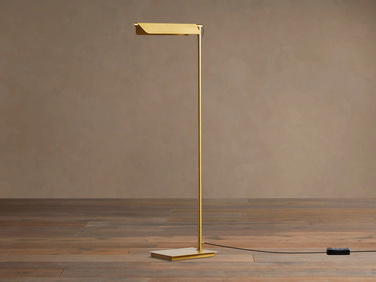 Close-up of Axle Brass Floor Lamp, showing its rectangular, pivoting shade and vertical pole in a brushed brass finish.
