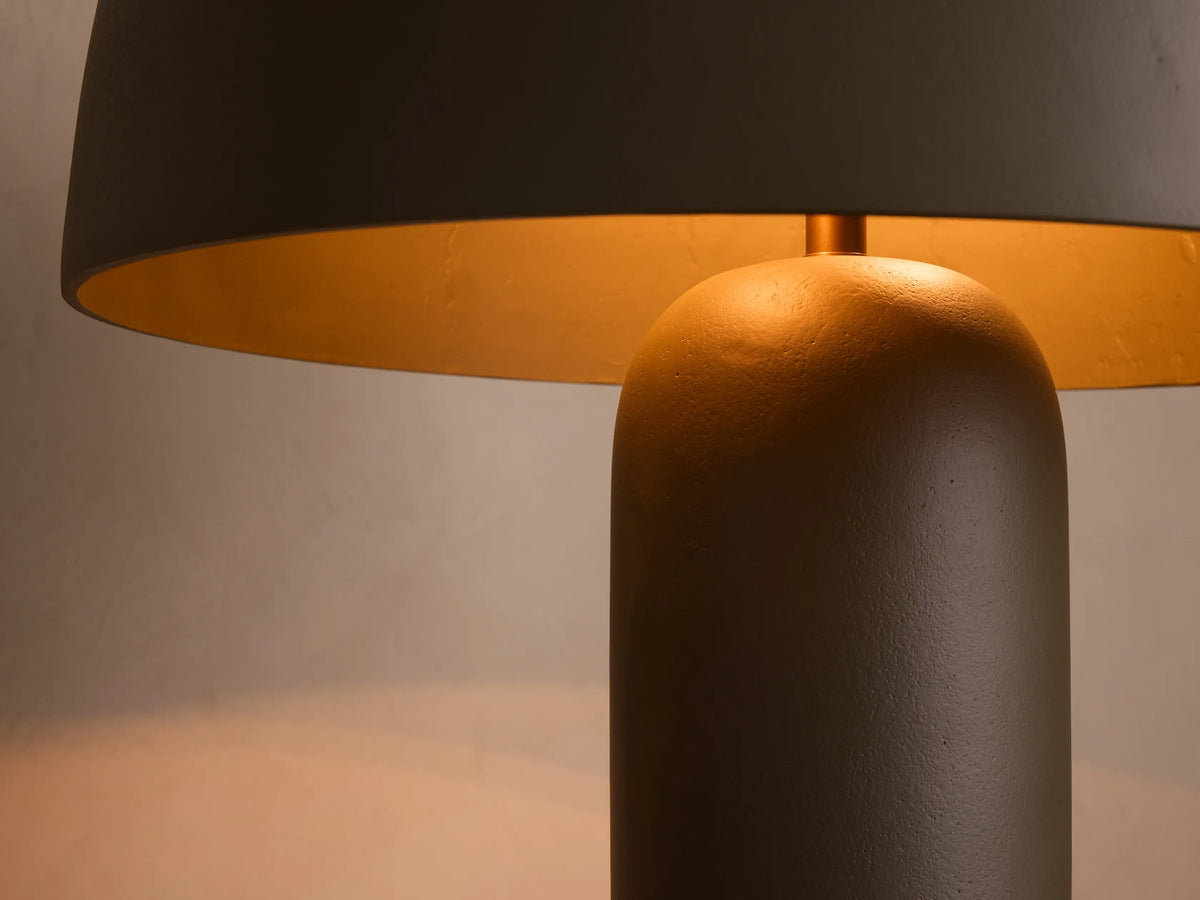 Front view of a dark olive green mushroom-shaped floor lamp with a thick cylindrical base, on light wood flooring.