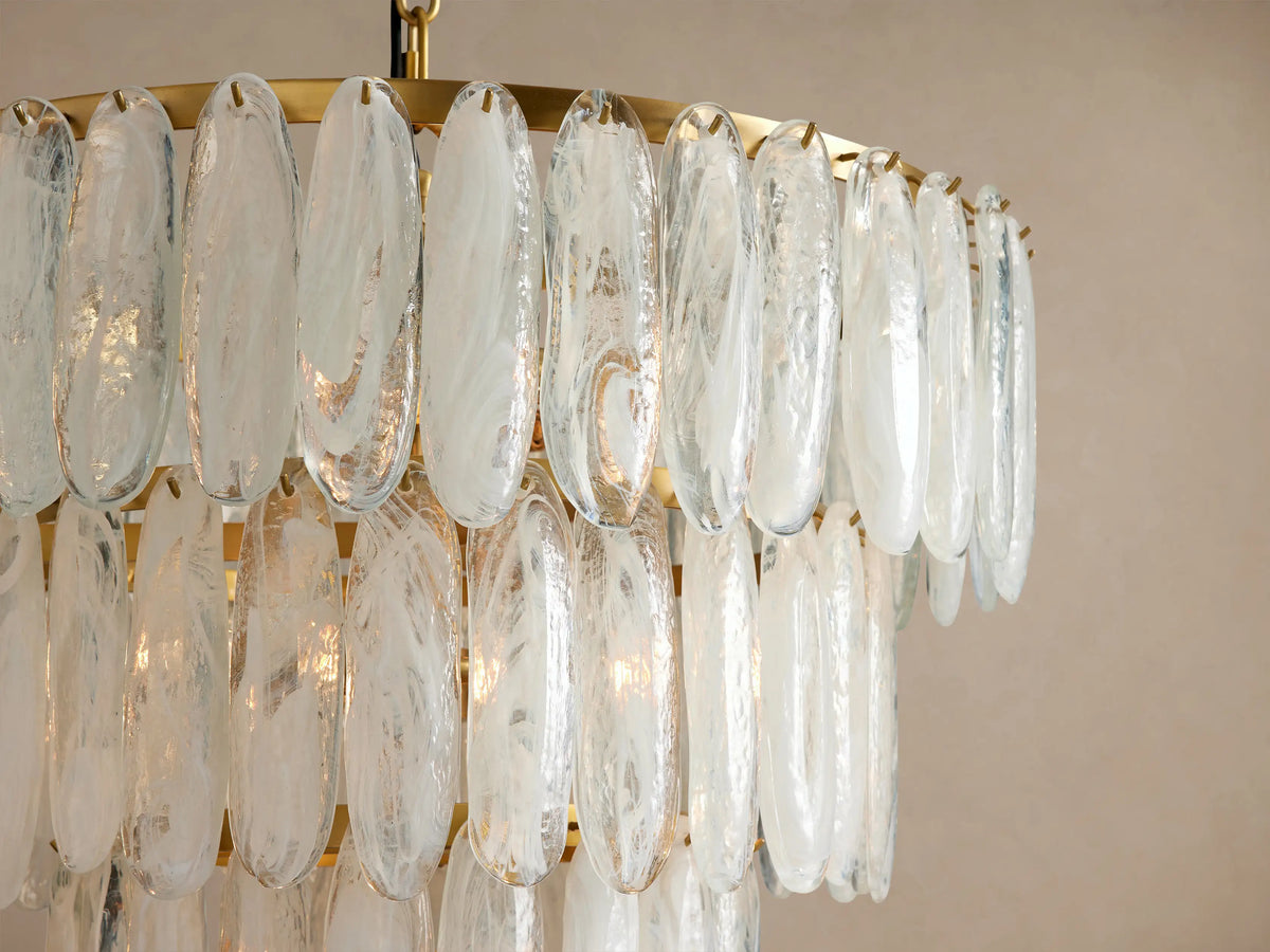 Verna Chandelier: Tiered round chandelier with layers of swirled clear glass pieces hanging from an antique brass frame.
