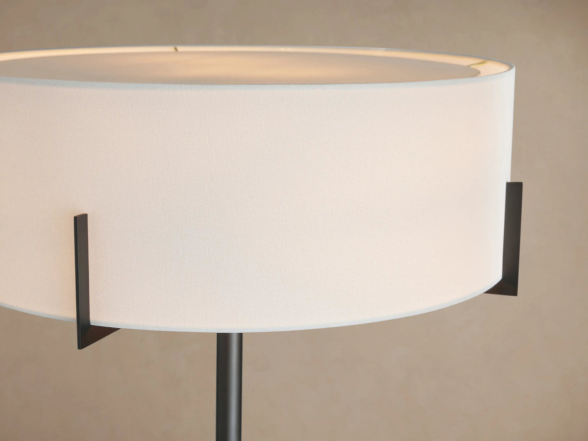 Frederic Floor Lamp with dark bronze pole, white linen drum shade, and black square base with round cream marble detail.