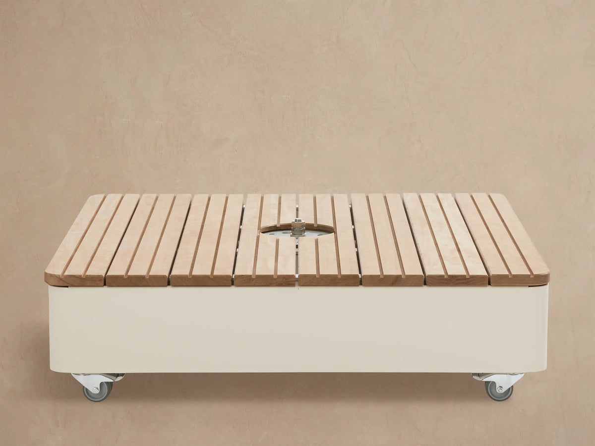 Icarus Outdoor Umbrella in Sand, partially open with a light beige canopy and white curved arm against a beige wall.