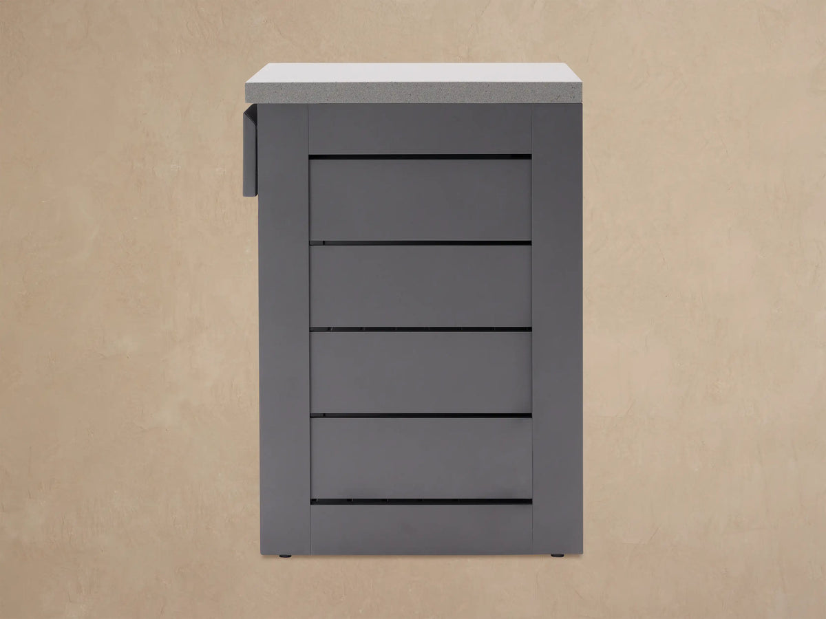 Dark gray aluminum outdoor kitchen cabinet with light gray stone top. Drawer is pulled open, showing interior.
