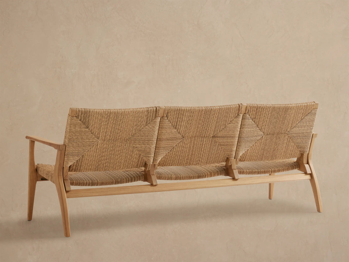 Mustique Outdoor Sofa: close-up, angled view of light teak frame, natural handwoven all-weather wicker with geometric patterns.