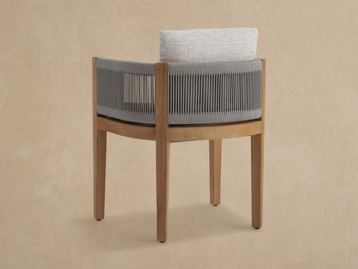 Newport Outdoor Dining Arm Chair, angled close-up. Grey Shardai Zinc rope weave, natural teak frame, light textured cushions.