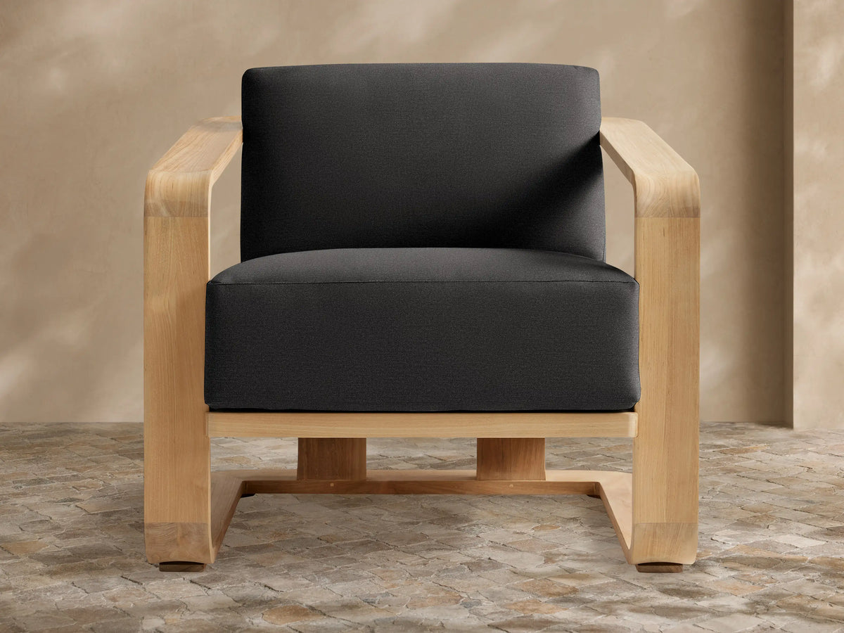 Sonoma Outdoor Lounge Chair with a light teak frame and deep Rosemount Graphite cushions, front view on a stone patio.
