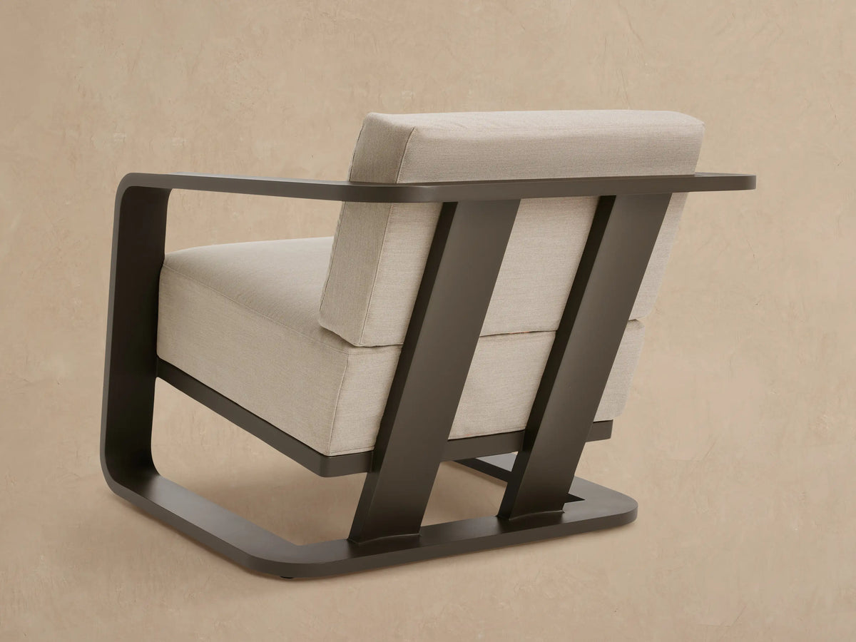 Close-up of Sonoma Outdoor Aluminum Lounge Chair's dark gray armrest and light beige fabric cushions.