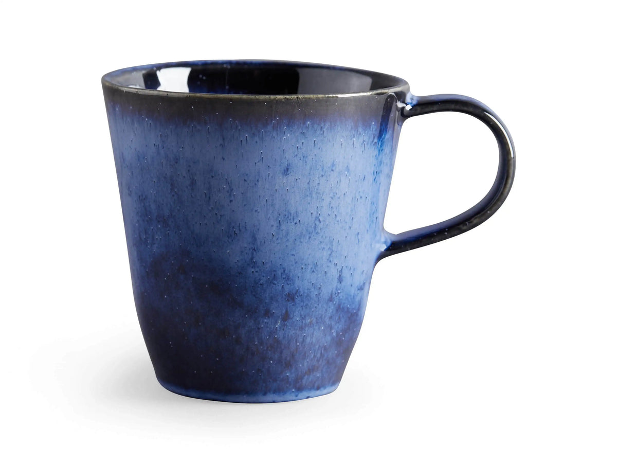 Twilight Mug in blue stoneware with a rich, reactive glaze, set beside matching indigo plates on a wooden table background.