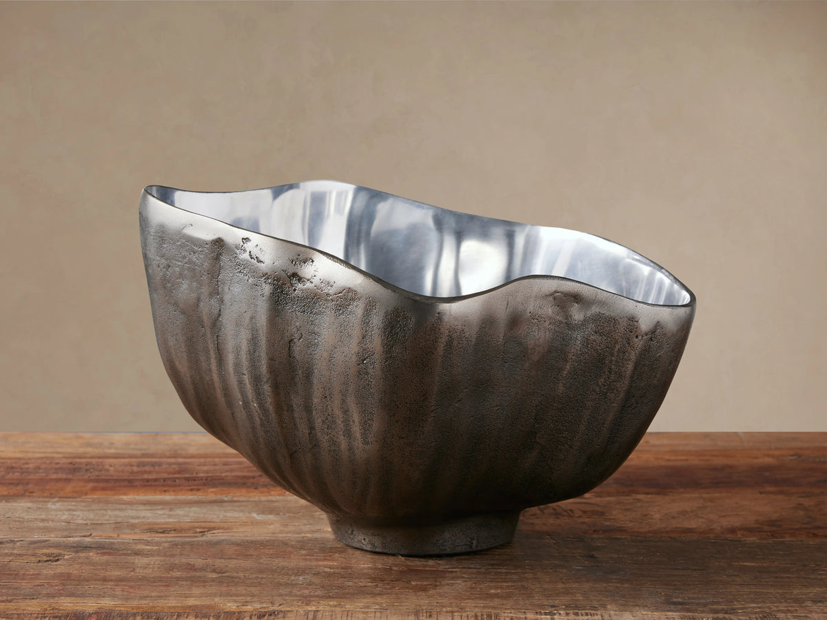 Arber Organic Bowl with a dark, textured exterior and shiny silver interior, sitting on a rustic wooden table.