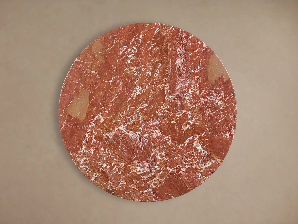 Front view of red marble Saint Germain Round Stone Dining Table with Dauphine Base, featuring twin dark oak pedestals.