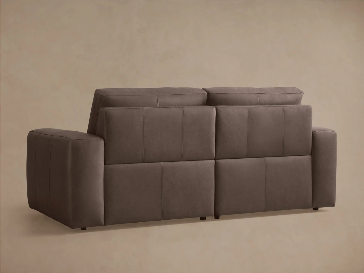 Brennan Leather Two-Piece Motion Sofa, dark taupe, viewed from the front-right with one extended reclined footrest, on a neutral background.